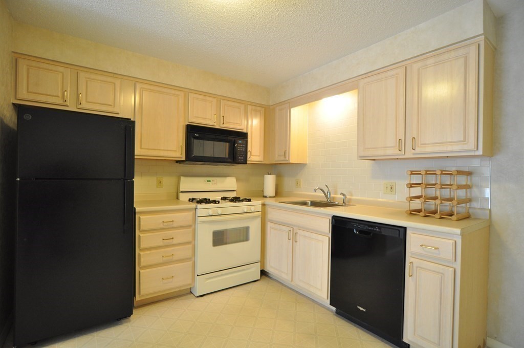 90 Beacon Street, Unit 8 Lawrence, MA 01843 - Photo 5 of 26 a kitchen with stainless steel appliances granite countertop a refrigerator stove a sink and a microwave
