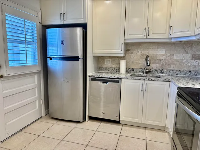 a kitchen with white cabinets and refrigerator