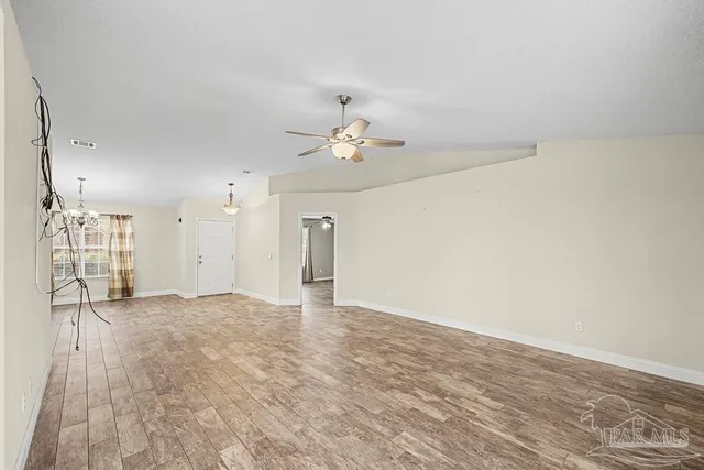 a view of an empty room with a chandelier fan