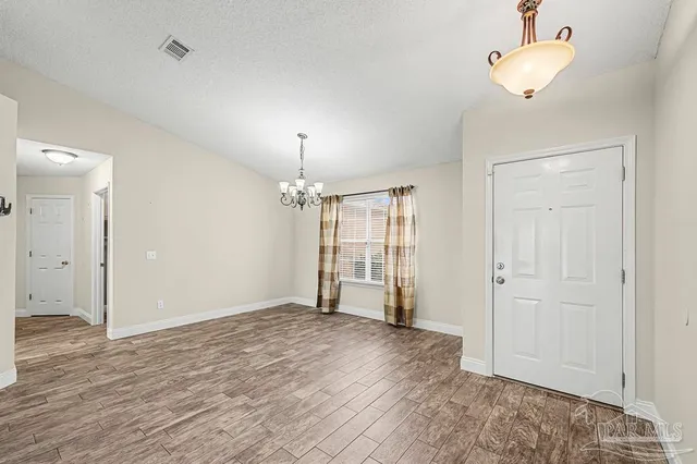 wooden floor in an empty room with a chandelier fan