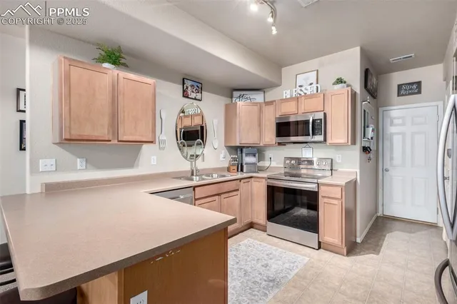 a kitchen with stainless steel appliances granite countertop a stove top oven a sink dishwasher and a refrigerator with wooden floor