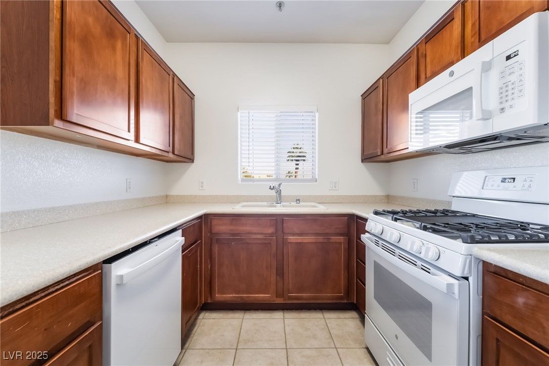 2291 West Horizon Ridge Parkway, Unit 12270 Henderson, NV 89052 - Photo 16 of 33 Kitchen featuring white appliances, light tile patterned floors, and brown cabinets