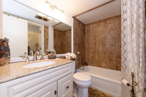 a bathroom with a granite countertop sink toilet mirror and shower