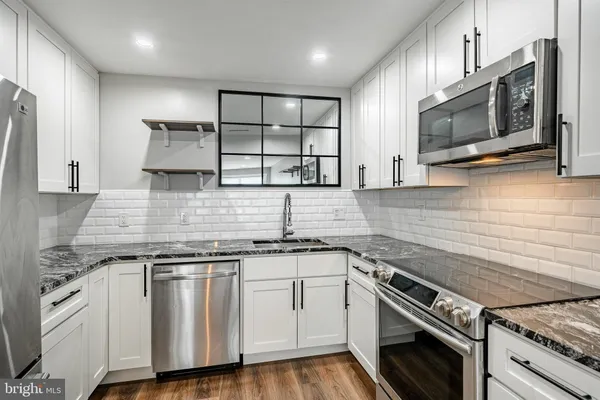 a kitchen with stainless steel appliances white cabinets and a stove top oven