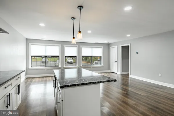 a view of kitchen island wooden floor living room and windows