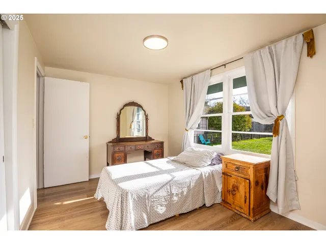 a bedroom with a bed and a dresser with wooden floor