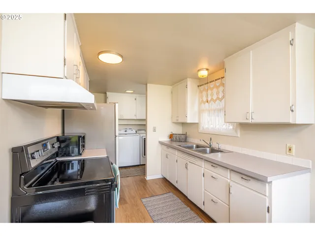 a kitchen with a sink wooden cabinets dining table chairs and a large window
