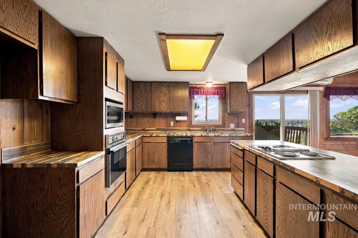 10201 Willis Road Middleton, ID 83644 - Photo 10 of 38 Wood-finish cabinetry, built-in wall oven and microwave, wood-finish flooring, built-in cooktop, and sliding glass doors