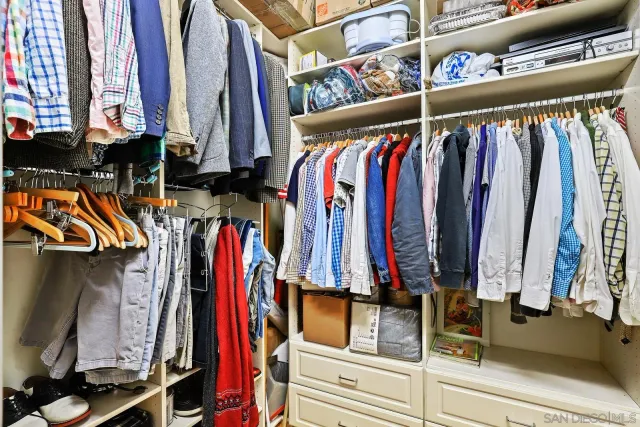a view of walk in closet with clothes and shoes
