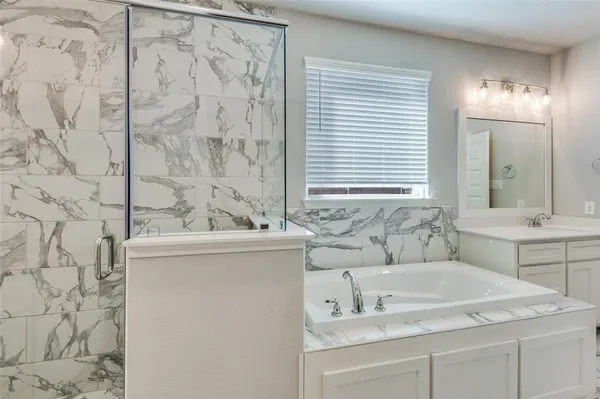 a bathroom with a granite countertop sink a mirror and a bathtub