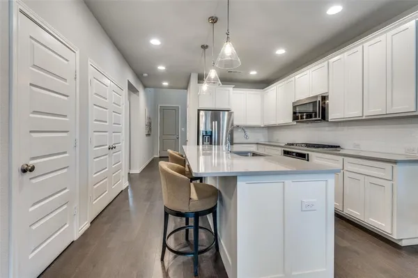 a kitchen with kitchen island white cabinets stainless steel appliances and a refrigerator