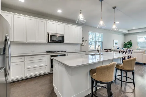 a kitchen with stainless steel appliances granite countertop a stove a sink a microwave a refrigerator and white cabinets