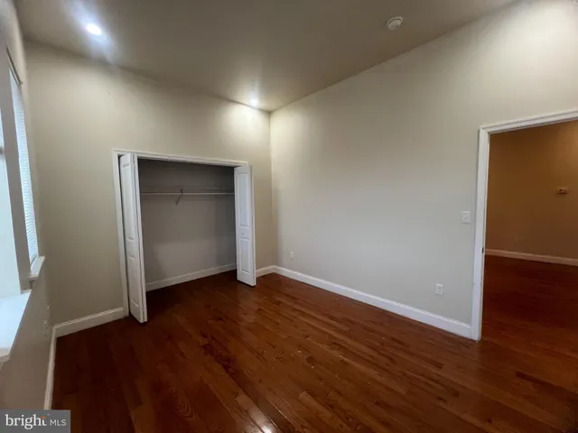 a view of an empty room with wooden floor and closet