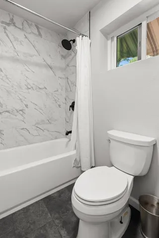 a white toilet sitting next to a bath tub and a shower