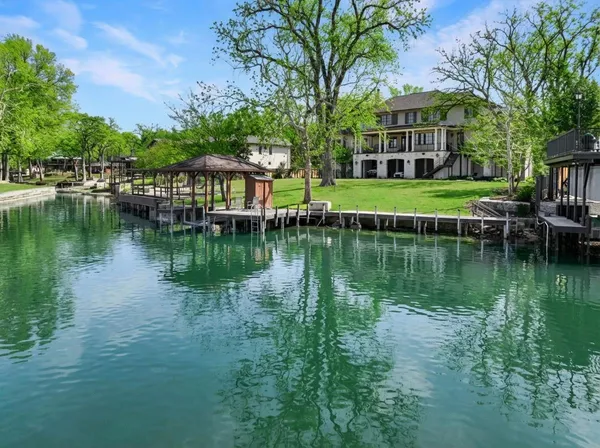 a view of a house next to a lake with a large trees