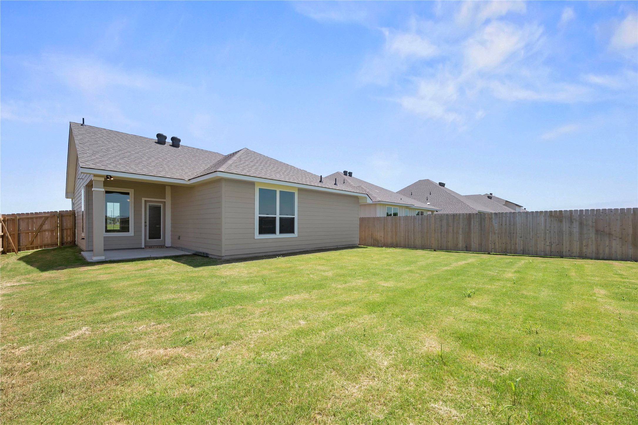 228 Gus Loop Georgetown, TX 78626 - Photo 19 of 19 A vibrant green lawn extends from a comfortable patio area to a robust wooden privacy fence.