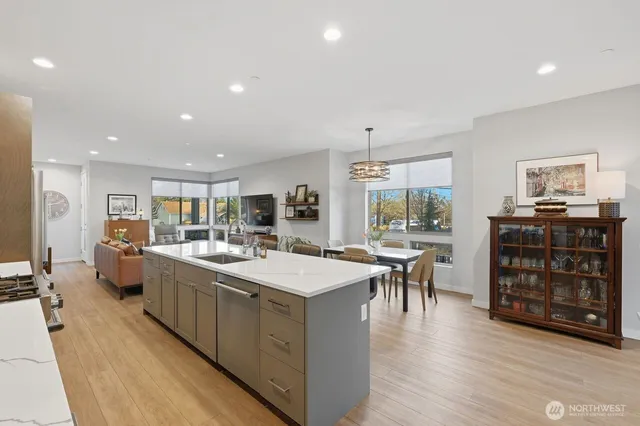 a large kitchen with stainless steel appliances a stove a sink dishwasher and a dining table with the living room view