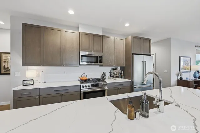 a kitchen with stainless steel appliances a sink a stove a refrigerator cabinets and a dining table