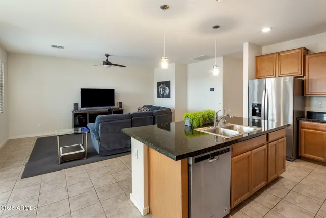 a kitchen with stainless steel appliances kitchen island granite countertop a sink and a refrigerator