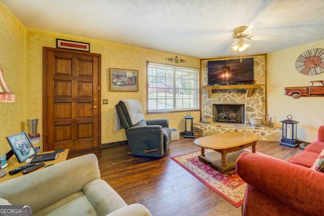 a living room with lots of furniture kitchen view and a wooden floor