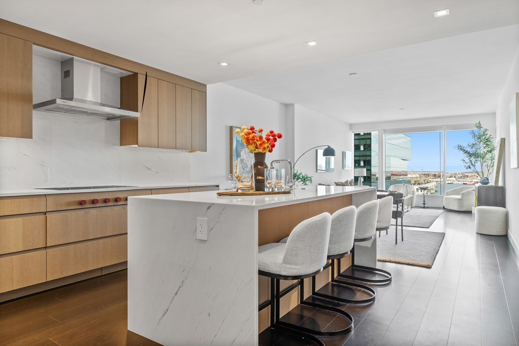 150 Seaport Boulevard, Unit 10D Boston, MA 02210 - Photo 3 of 23 a kitchen with a dining table chairs sink and white cabinets