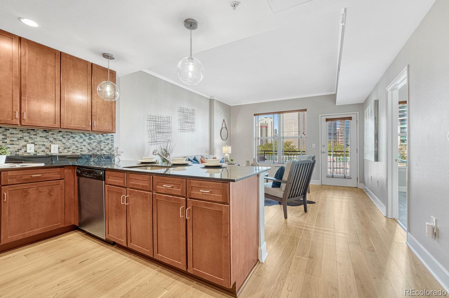 1975 Grant Street, Unit 509 Denver, CO 80203 - Photo 6 of 30 a kitchen with stainless steel appliances granite countertop wooden cabinets a table and chairs
