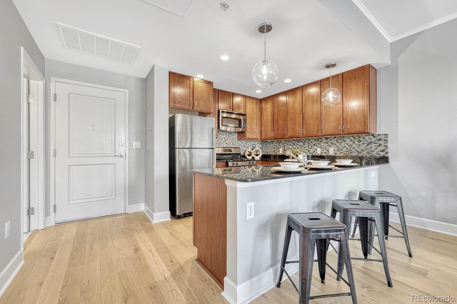 1975 Grant Street, Unit 509 Denver, CO 80203 - Photo 7 of 30 a kitchen with stainless steel appliances kitchen island granite countertop a refrigerator and a stove top oven