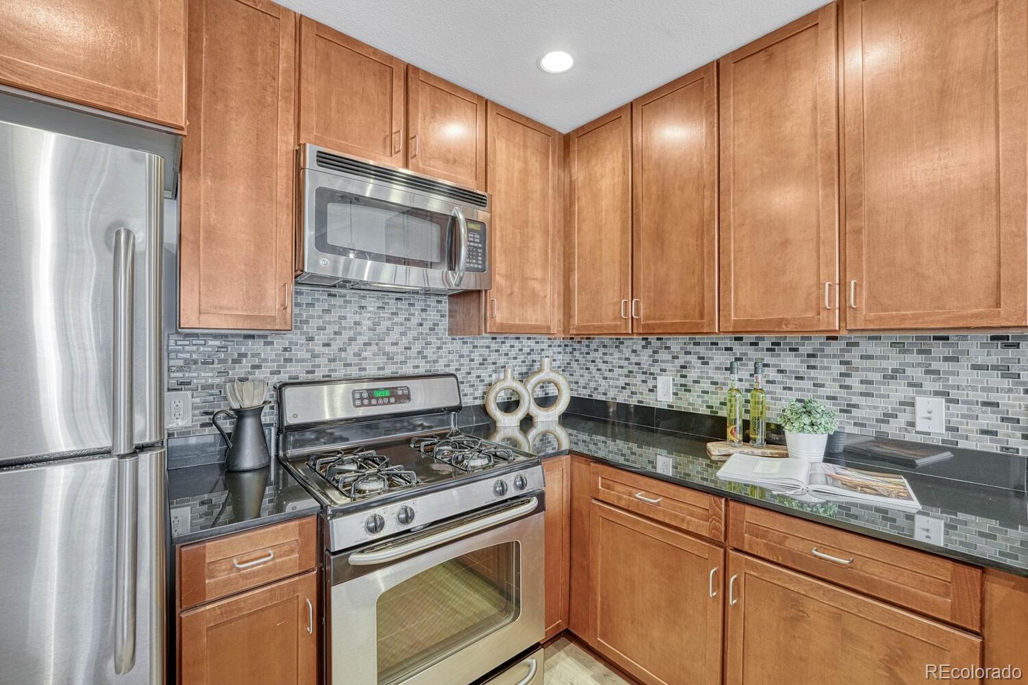 1975 Grant Street, Unit 509 Denver, CO 80203 - Photo 9 of 30 a kitchen with stainless steel appliances granite countertop a sink stove and refrigerator