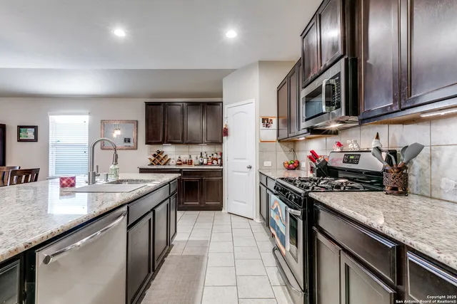 a kitchen with stainless steel appliances granite countertop a sink stove microwave and cabinets