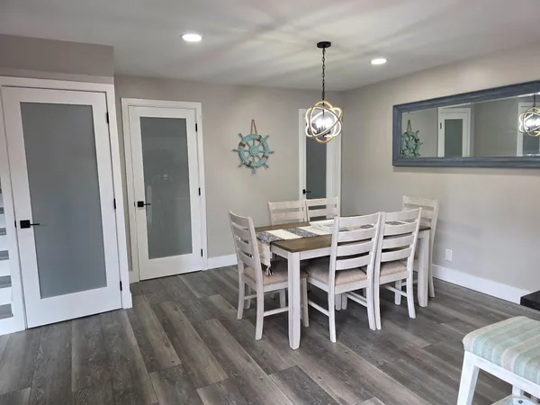 a dining room with wooden floor a chandelier a wooden table and chairs
