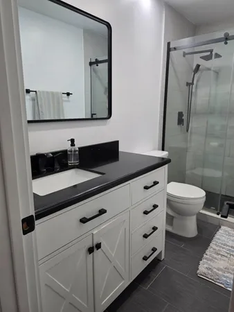 a bathroom with a granite countertop sink mirror vanity and toilet