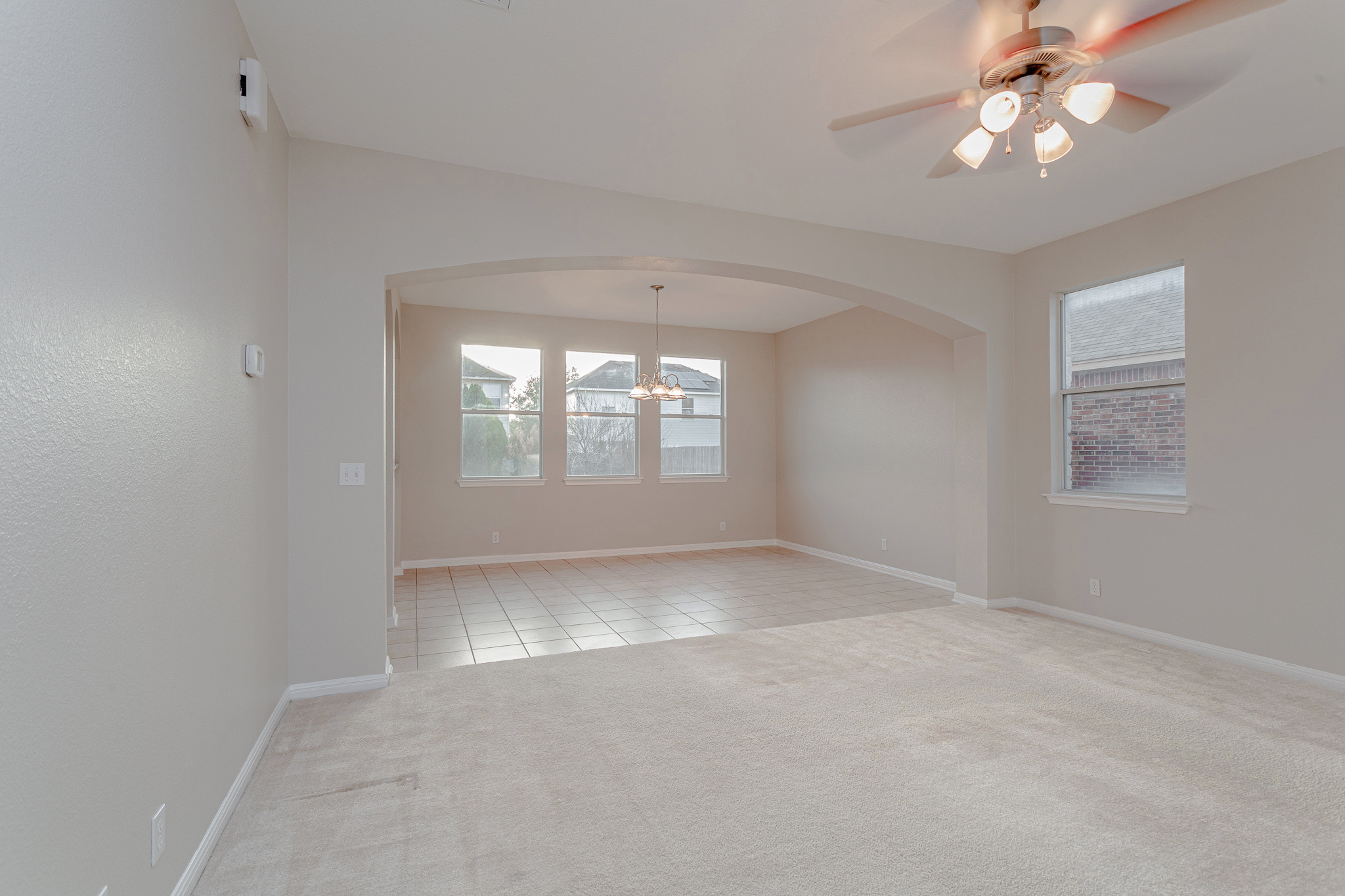 19201 Mangan Way Pflugerville, TX 78660 - Photo 18 of 29 Spare room with light carpet, ceiling fan, light tile patterned floors, a chandelier, and arched walkways