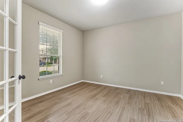 an empty room with wooden floor and windows