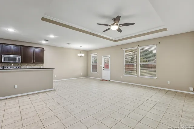 a view of an empty room with kitchen view and a window