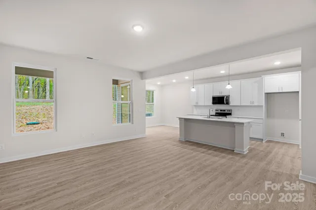 a view of kitchen with stainless steel appliances kitchen island wooden floors and living room view