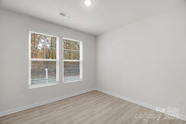 a view of an empty room with wooden floor and windows