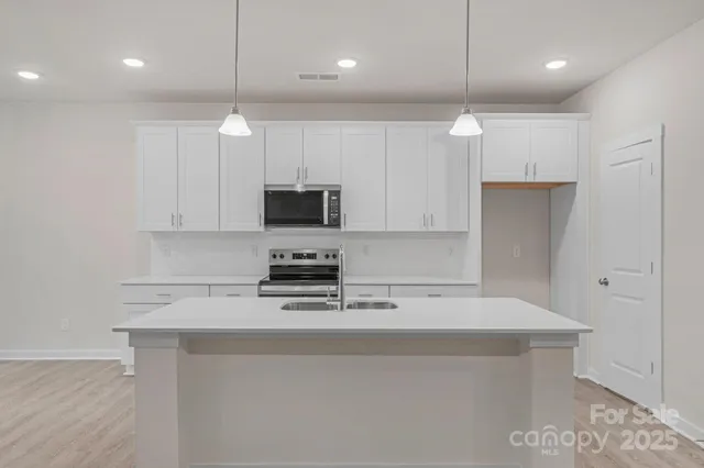 a kitchen with kitchen island white cabinets stainless steel appliances and wooden floor