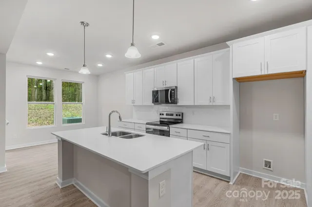 a kitchen with stainless steel appliances a sink a stove a refrigerator and cabinets