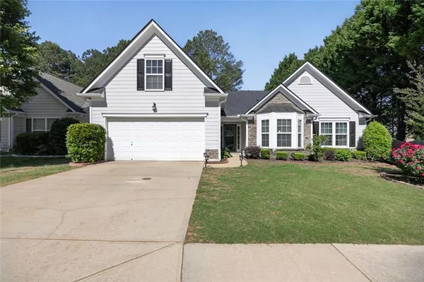 a front view of a house with a garden and trees