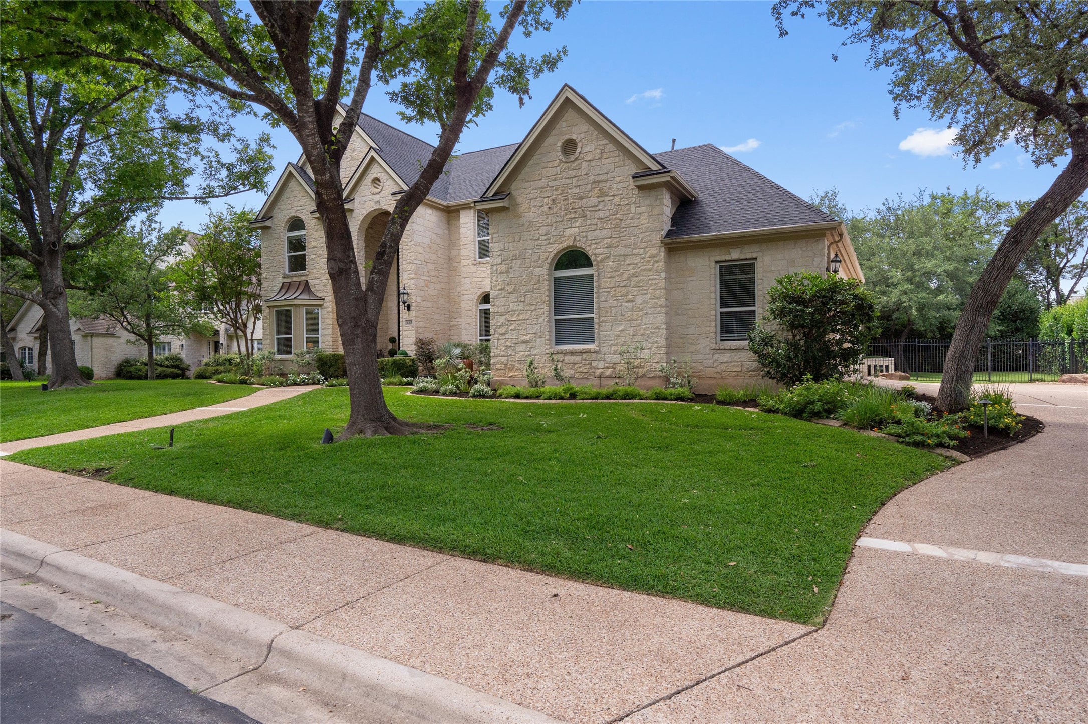 4313 Rio Robles Drive Austin, TX 78746 - Photo 2 of 40 Mature trees frame this grand stone residence with a pristine lawn and elegant landscaping.