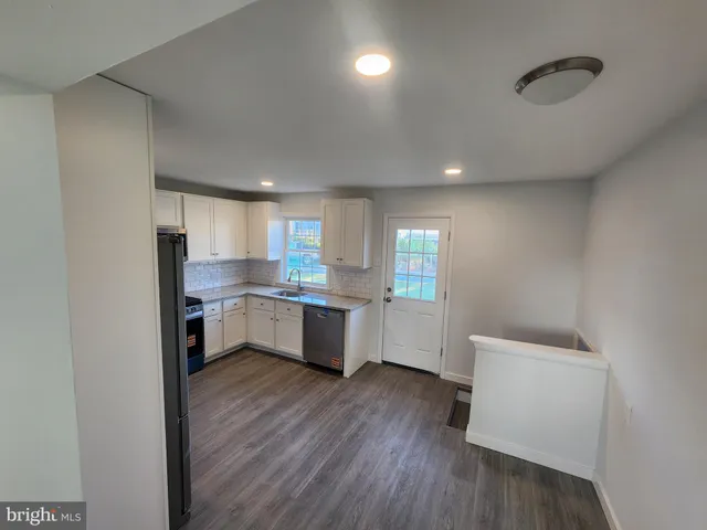 a kitchen with a refrigerator and white cabinets