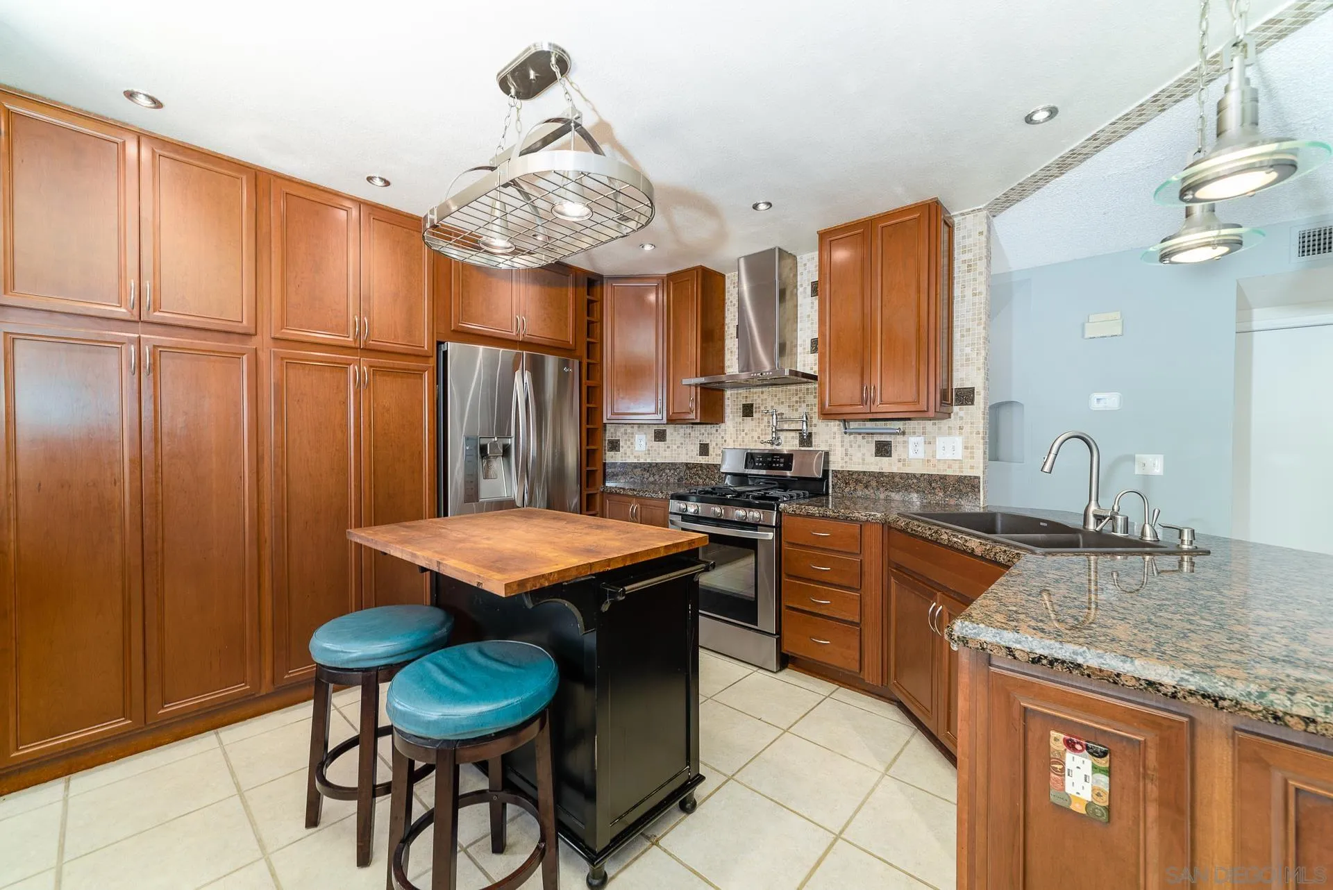 5268 Champlain Street Oceanside, CA 92056 - Photo 13 of 40 a kitchen with stainless steel appliances granite countertop wooden cabinets a dining table and chairs