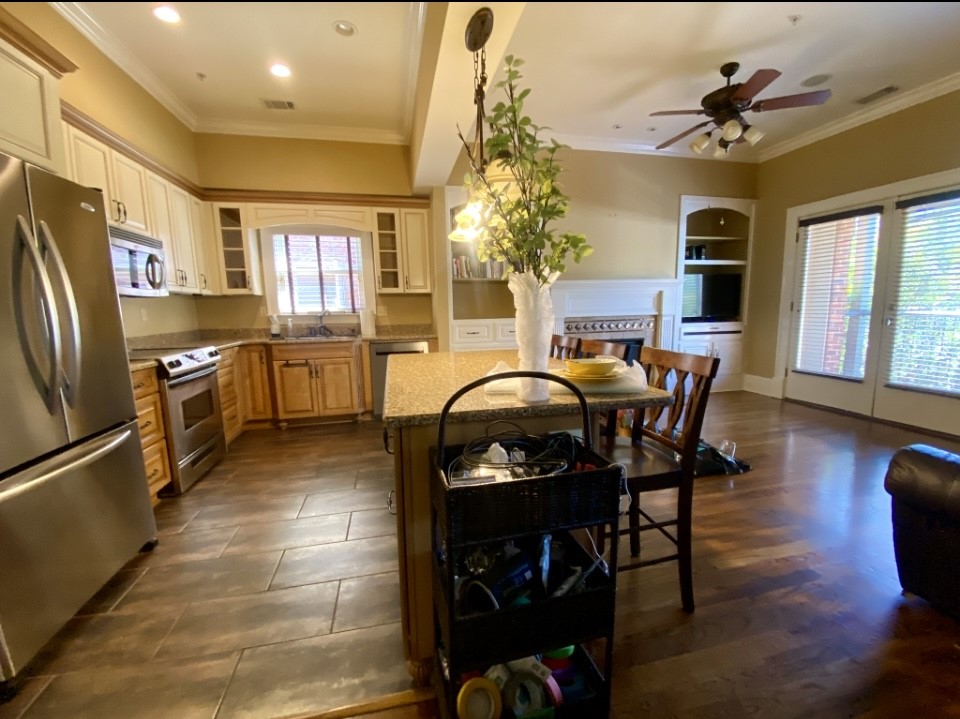 a kitchen with stainless steel appliances granite countertop a stove top oven a refrigerator a dining table and chairs with wooden floor