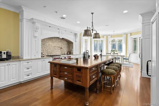 a kitchen with stainless steel appliances granite countertop a stove a sink a refrigerator and wooden floors