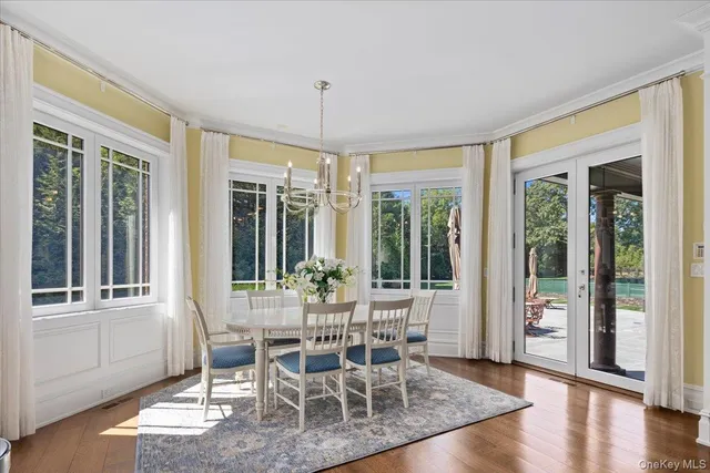 a dining room with wooden floor a chandelier glass table and chairs