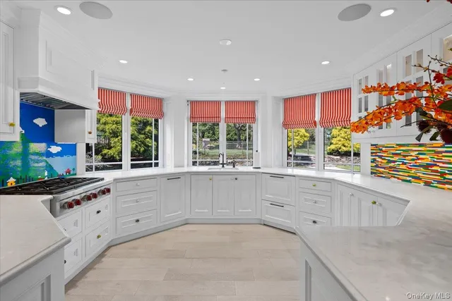 a large white kitchen with granite countertop a sink and white cabinets