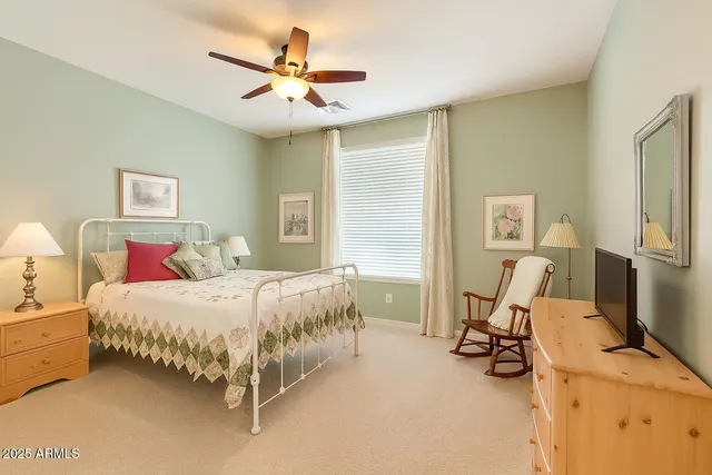 a bedroom with a bed a couch and a ceiling fan