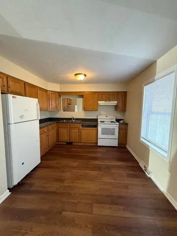 a kitchen with granite countertop a refrigerator and a stove top oven