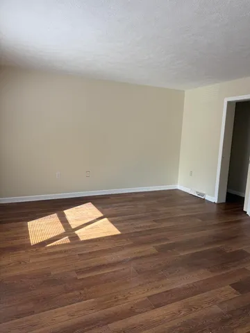 a view of an empty room and wooden floor and a window