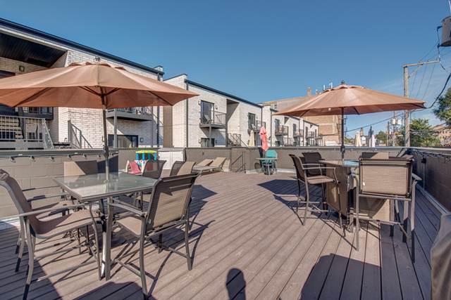 2453 West Irving Park Road, Unit 1E Chicago, IL 60618 - Photo 19 of 23 a patio with a table and chairs under an umbrella